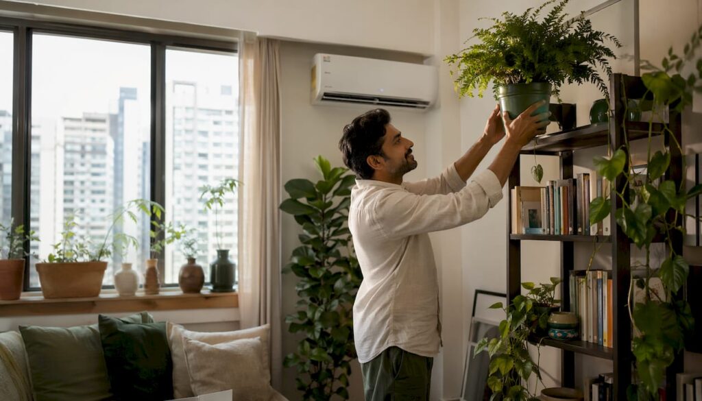 Man arranging plant near air conditioner indoors