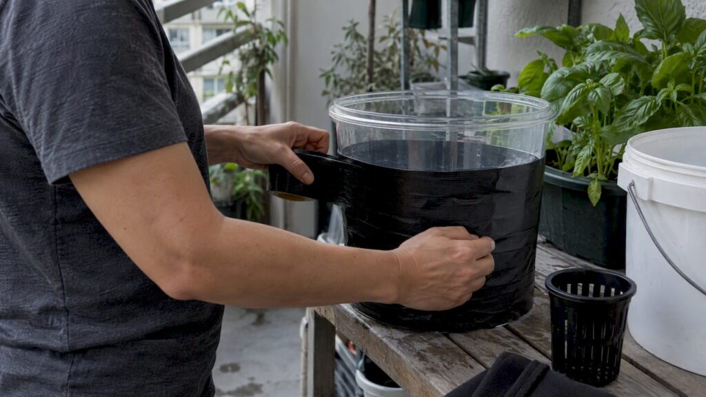 Hands covering hydroponic reservoir to block light